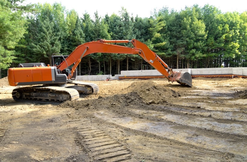 A digger moving topsoil at a construction site.